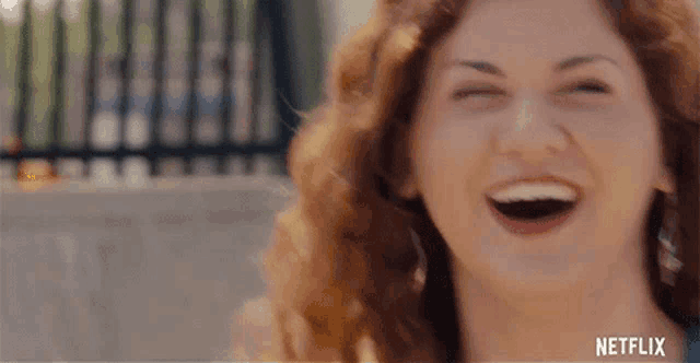 a close up of a woman laughing with her eyes closed and her mouth open .