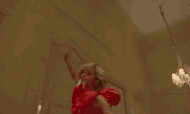 a woman in a red dress is dancing in a room .