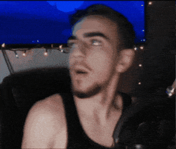 a man in a black tank top is sitting in front of a tv
