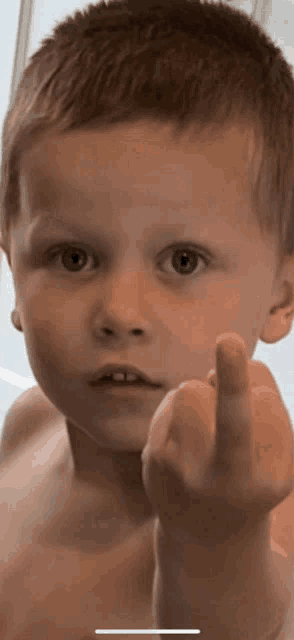 a shirtless young boy giving the middle finger