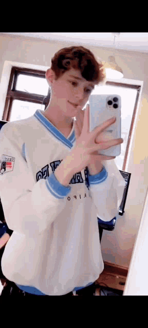 a young man is taking a picture of himself in a mirror with his phone .