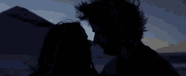 a man and a woman are looking into each other 's eyes in the dark