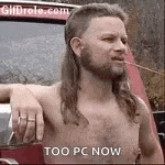 a shirtless man with a mullet and a beard is standing in front of a car .