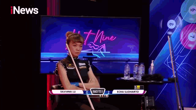a woman is playing pool in front of a sign that says inews