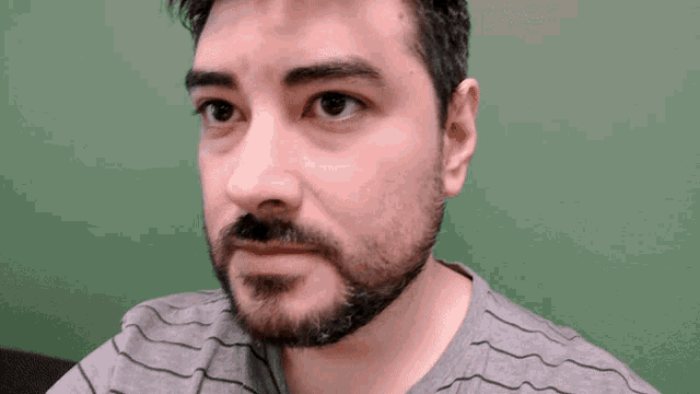 a man with a beard is wearing a grey shirt