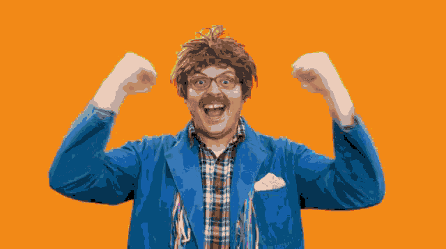 a man in a blue jacket and plaid shirt holds his arms up in the air