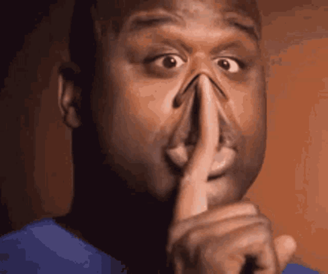 a man is making a shhh gesture with his finger in his mouth
