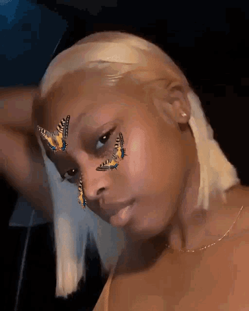 a woman with butterflies painted on her face looks at the camera