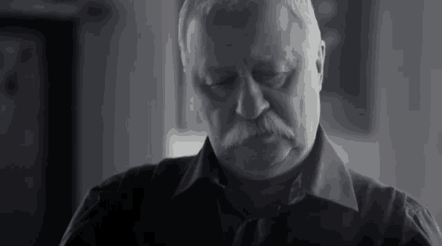 a black and white photo of an older man with a mustache .