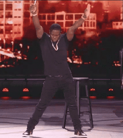 a man is standing on a stage with his arms in the air .