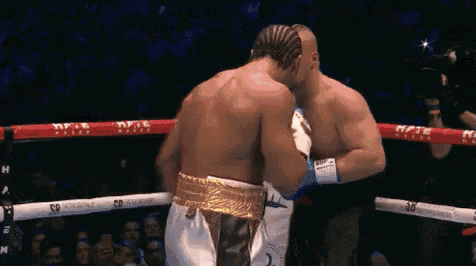 two men are fighting in a boxing ring and one is wearing a gold belt .