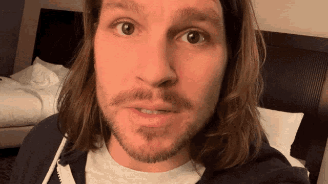 a man with long hair and a beard looks surprised