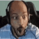a man with a beard is wearing headphones and making a funny face .