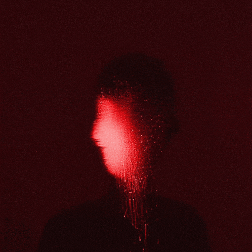a red light is shining on a person 's face in the dark