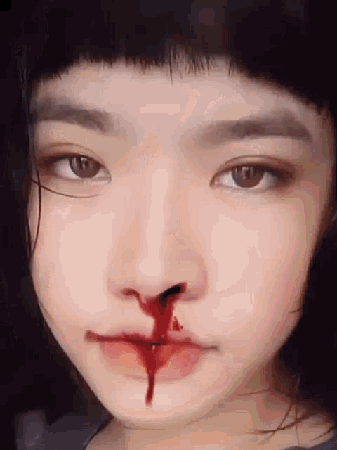 a close up of a woman 's face with blood coming out of her nose .