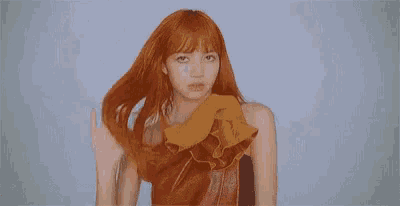 a woman with red hair is wearing a red and yellow dress and looking at the camera .
