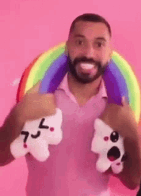 a man with a beard is holding two stuffed animals in front of a rainbow .