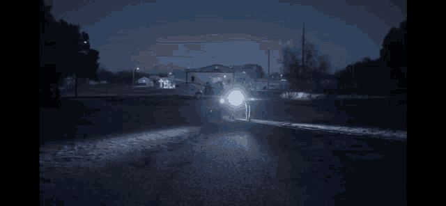 a car is driving down a road at night with its headlights on .