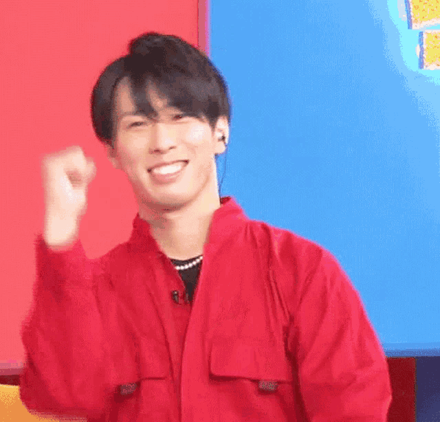 a man in a red jacket is making a fist and smiling .