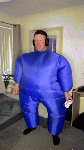 a man in a blue inflatable suit is holding a playstation controller