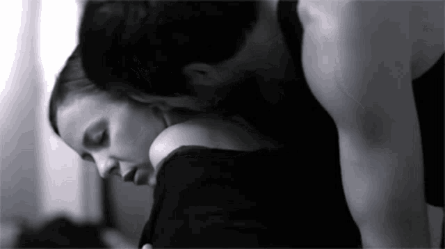 a man kissing a woman on the neck in a black and white photo .