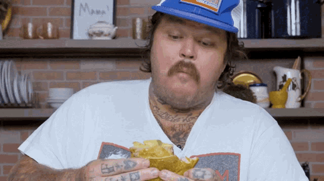 a man wearing a blue hat eating a sandwich