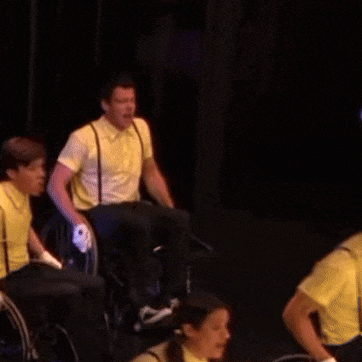 a man in a yellow shirt is riding a wheelchair