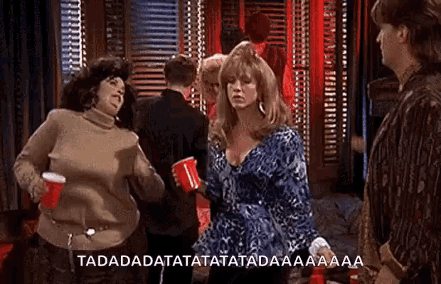 a group of women are dancing in a room and one of them is holding a red cup that says tadadatatatata