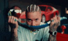 a man with dreadlocks is holding a blue rope around his face .
