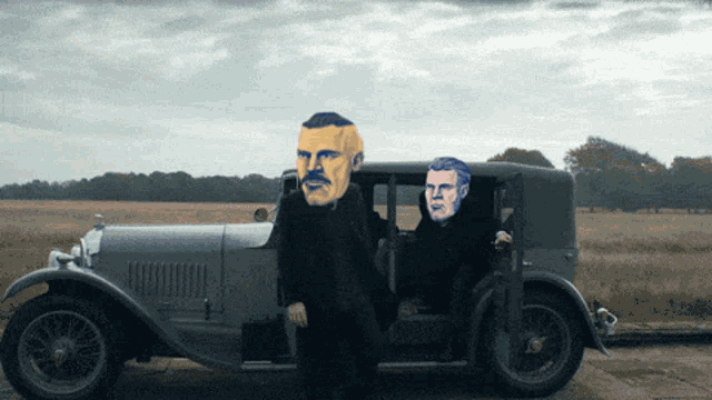 a man with a mustache is standing next to a car with two men in it