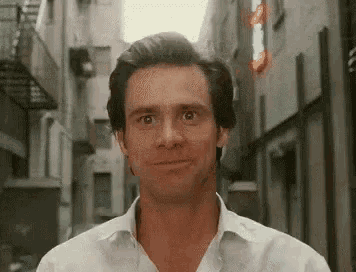 a man in a white shirt is standing in an alleyway and smiling .