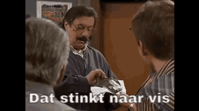 a group of men are standing around a table and one of them is holding a bag that says dat stinkt naar vis