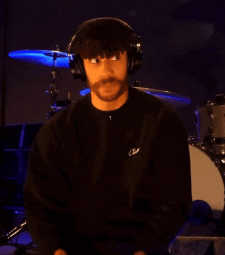 a man wearing headphones and a black shirt that says cave on it