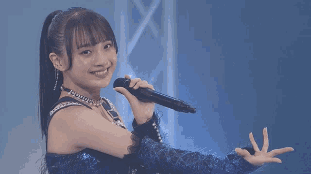 a woman in a blue dress is singing into a microphone and smiling