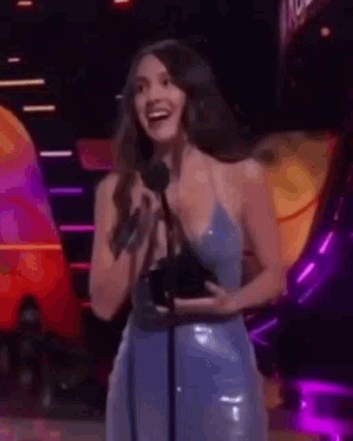 a woman in a blue dress is holding a microphone and speaking into it .