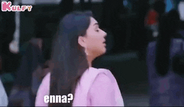 a woman in a pink shirt is standing in front of a crowd and asking , `` enna ? '' .