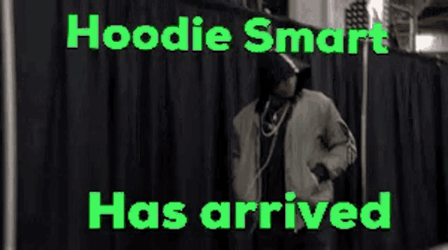 a man is standing in front of a black curtain with the words " hoodie smart has arrived "