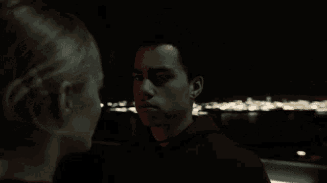 a man and a woman are looking into each other 's eyes in the dark .