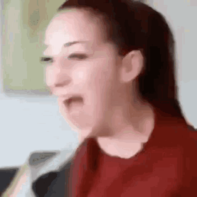 a woman in a red shirt is making a funny face with her mouth open .