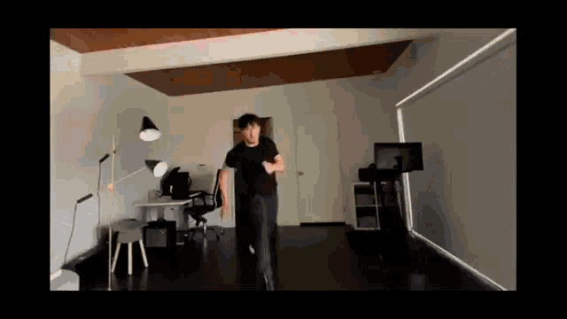 a man in a black shirt is walking in a room
