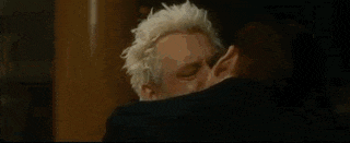 a man and a woman are kissing in a room in front of a window .