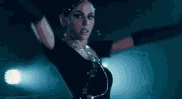 a woman is dancing on a stage with her arms outstretched in a dark room .