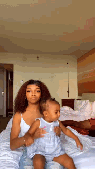 a woman is sitting on a bed with a baby in her lap .