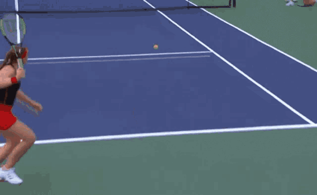 a woman wearing a red headband is standing on a tennis court .