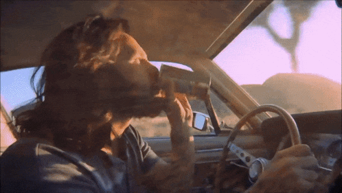 a man in a car drinking from a cup