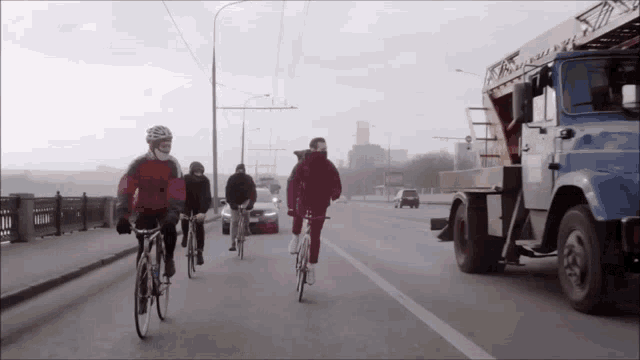 a group of people riding bikes down a street with a truck behind them that says ' a ' on it