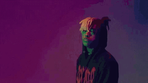 a man in a black hoodie is standing in front of a purple and blue background .