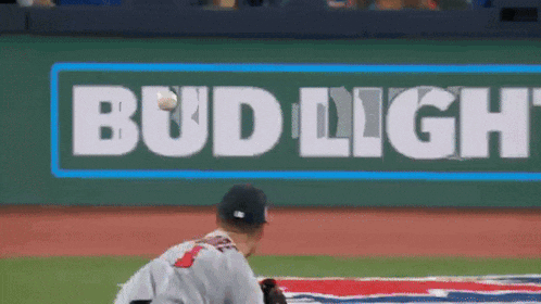 a baseball player is throwing a ball in front of a bud light sign
