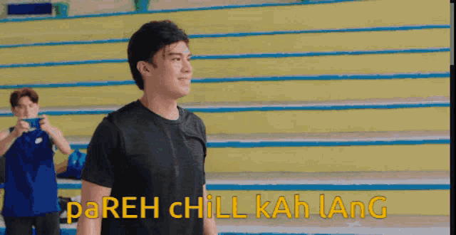 a man in a black shirt stands in front of a yellow staircase with the words dareh chill kah lang written in yellow