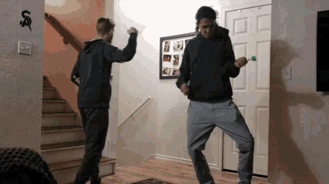 two men are dancing in a hallway with the letter s on the wall above them